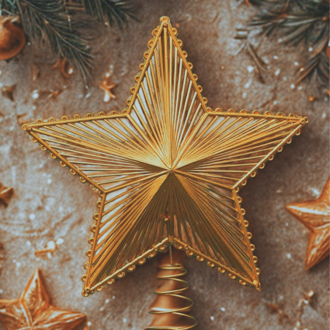 Gold star-shaped cookie on a textured surface with Christmas decorations.